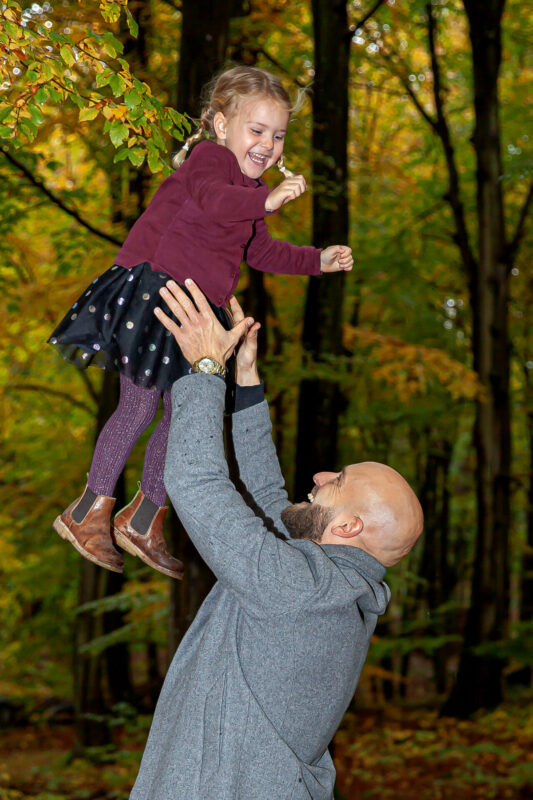 Far kaster datter op i luften ude i skoven